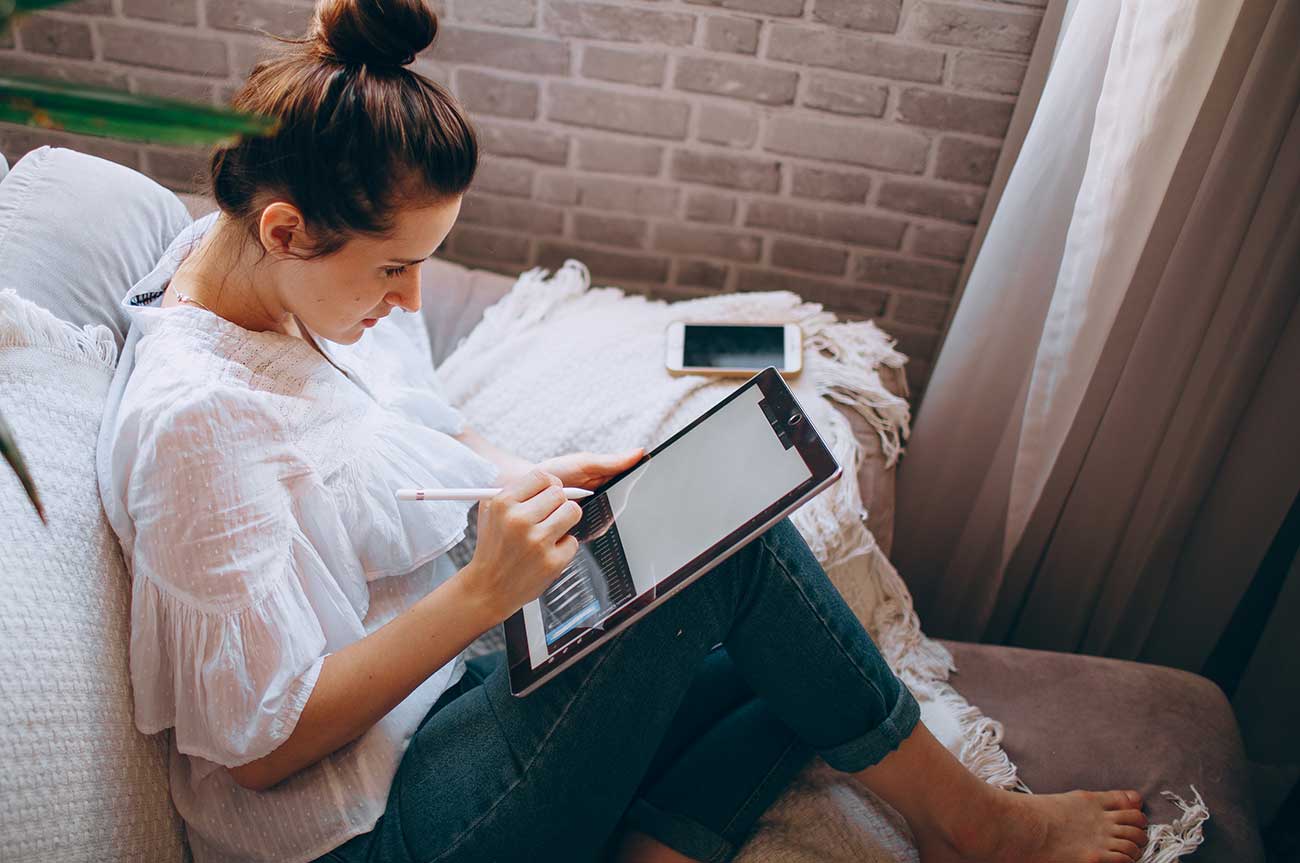 a woman sitting on a bed using a tablet