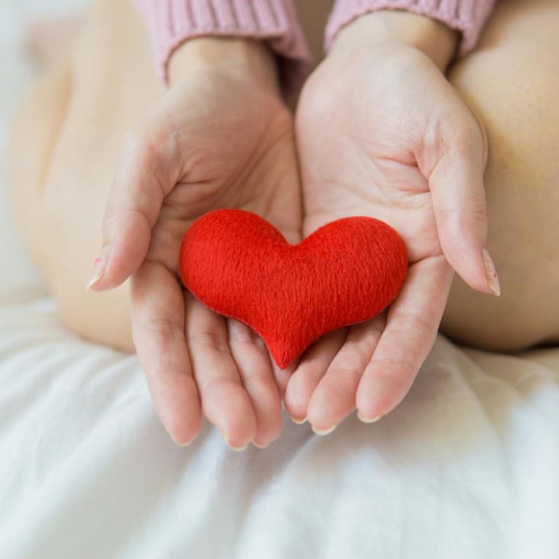 a woman holding a red cloth heart in her hands