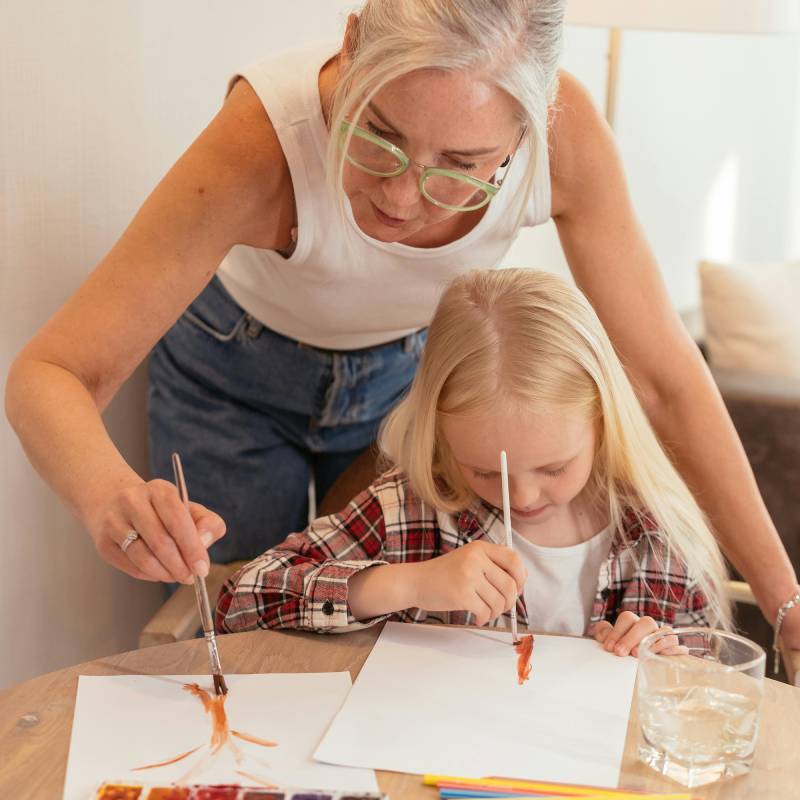 a woman and a little girl painting at a table
