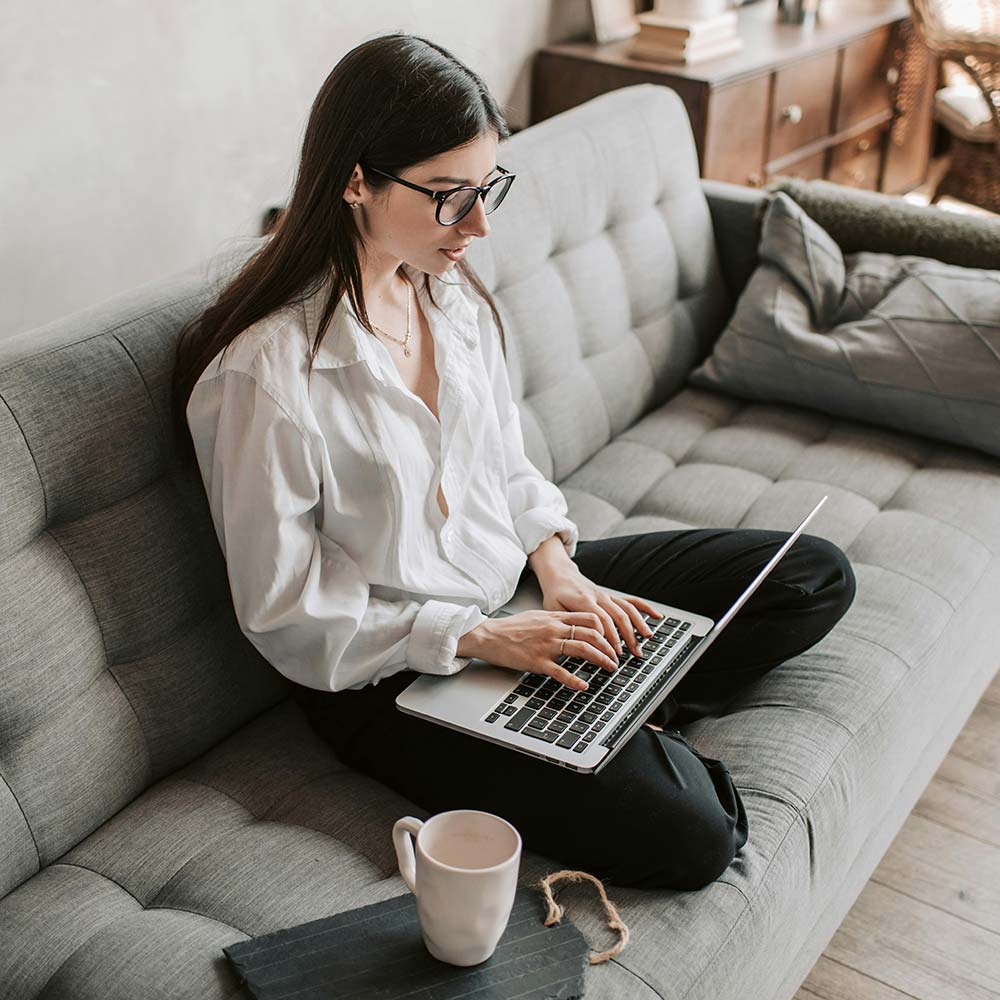 a woman sitting on a couch using a laptop