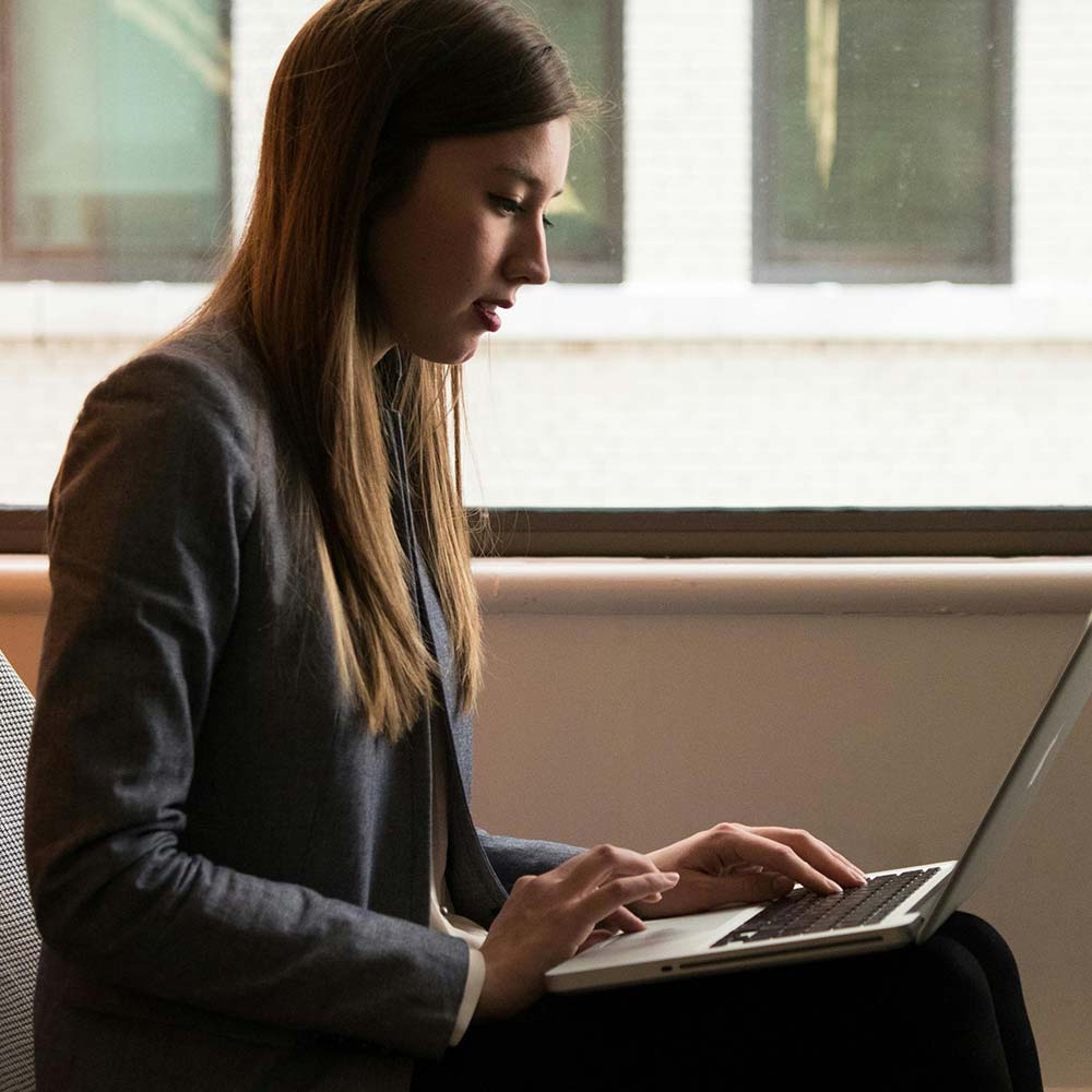 a woman sitting on a bench using a laptop computer