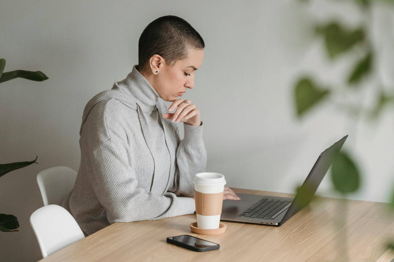 a woman sitting at a table with a laptop and a cup of coffee
