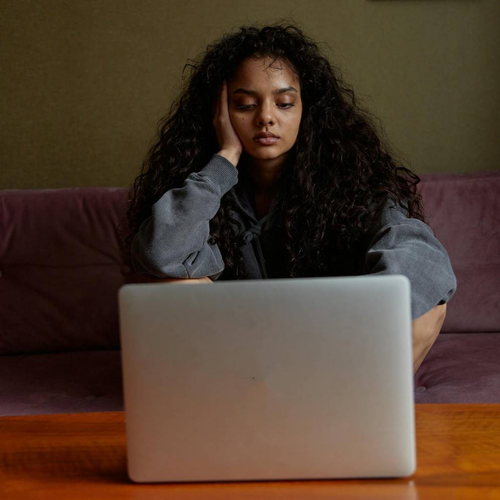 a woman sitting on a couch looking at a laptop
