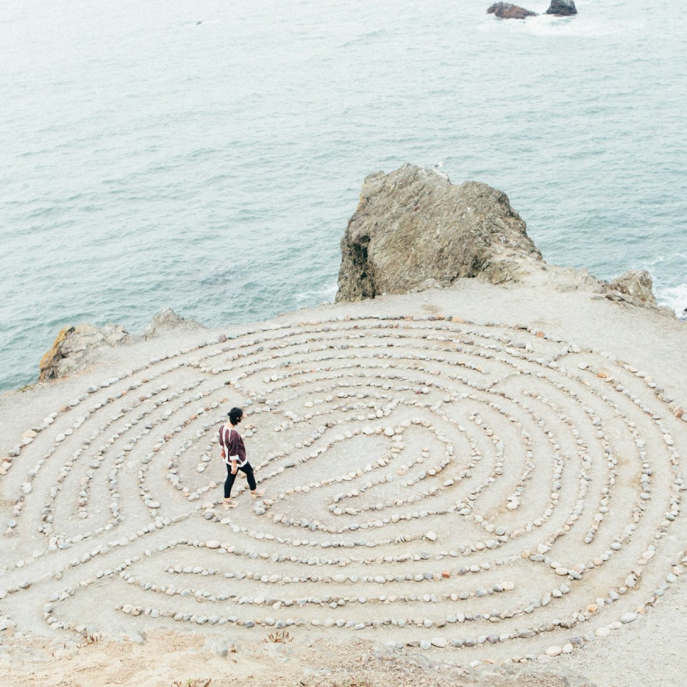 a man standing in the middle of a maze by the ocean