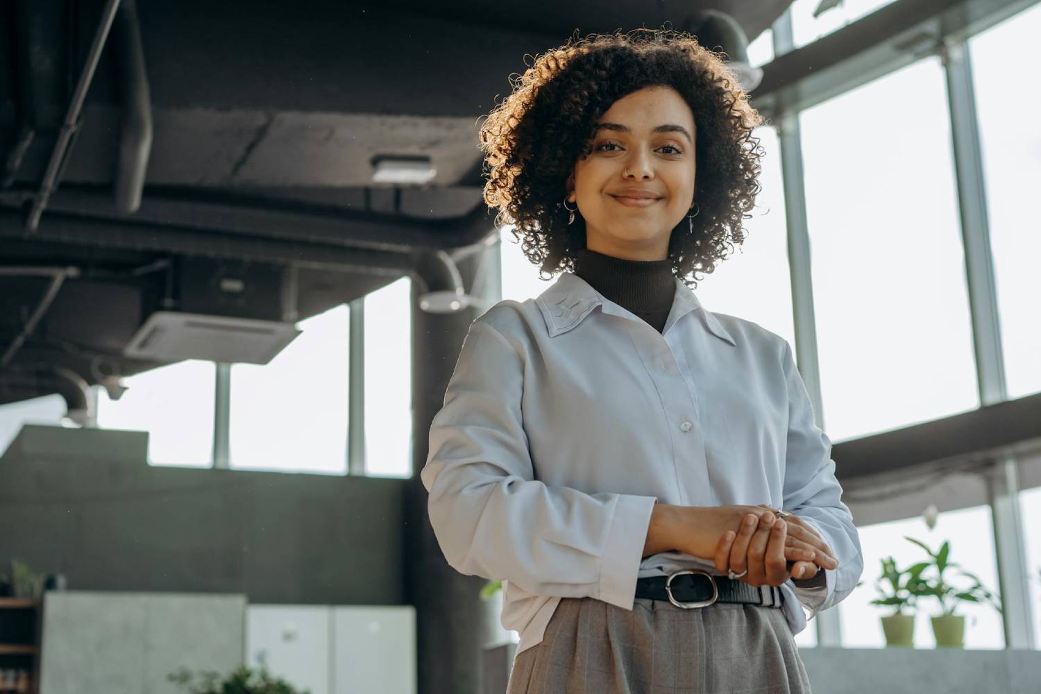 woman with curly hair standing in a bright office space