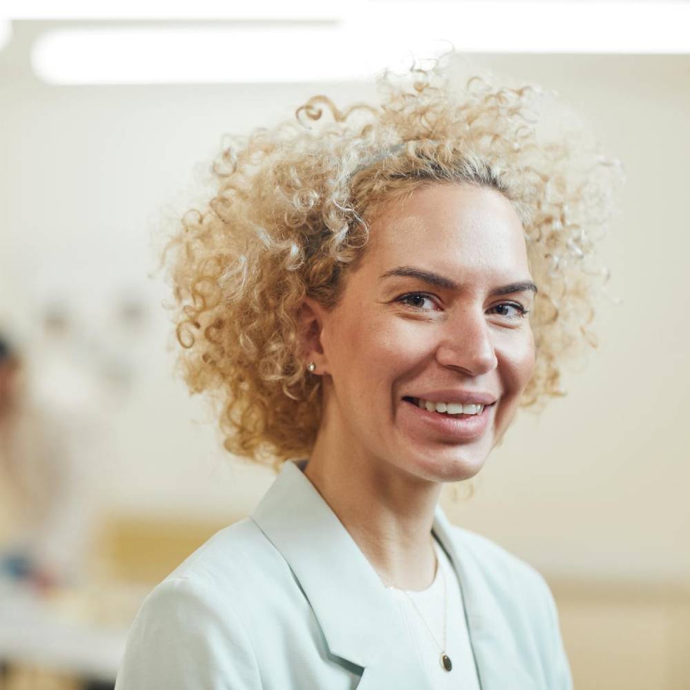 woman with curly blonde hair smiling at camera