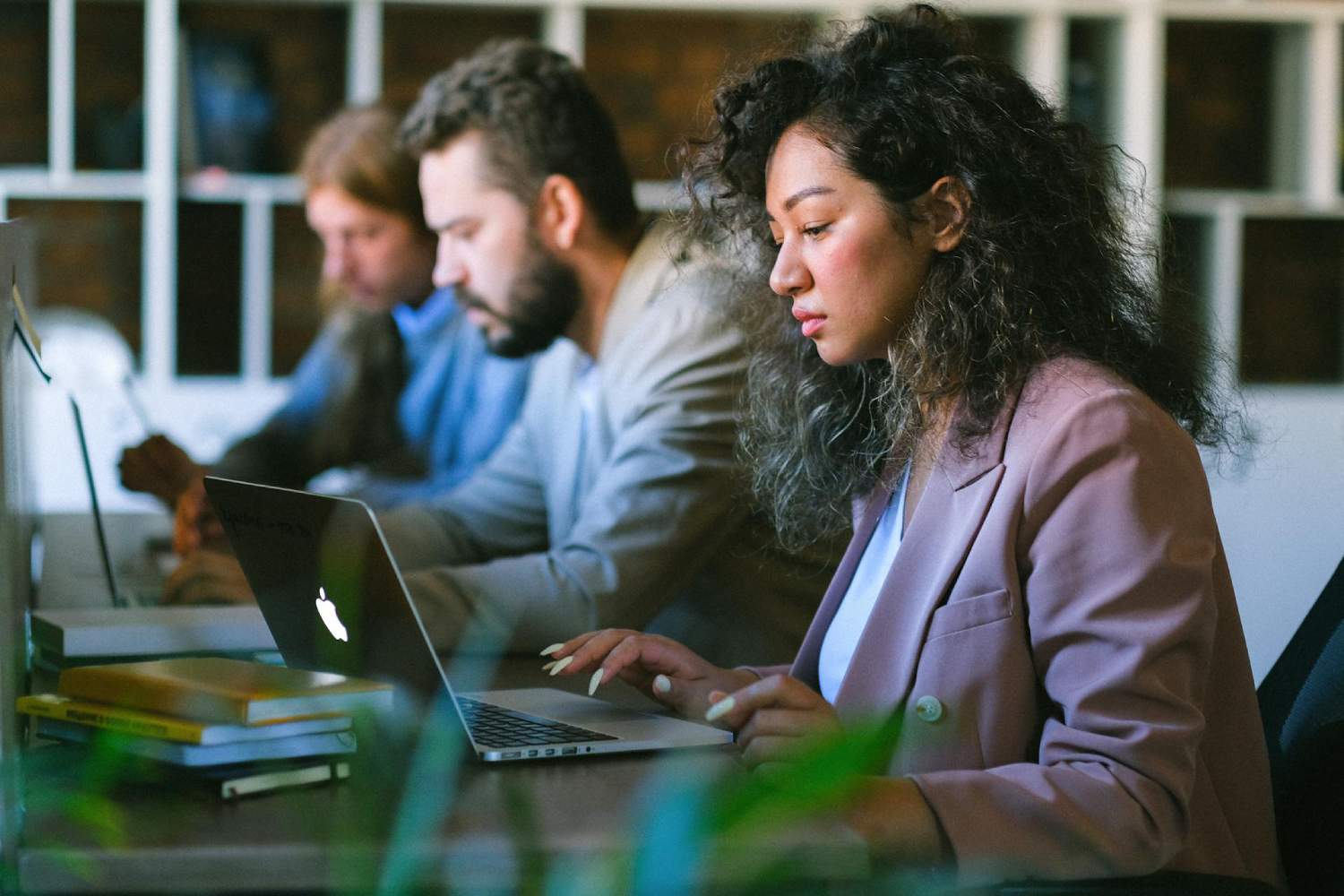 a group of people sitting at a table with laptops