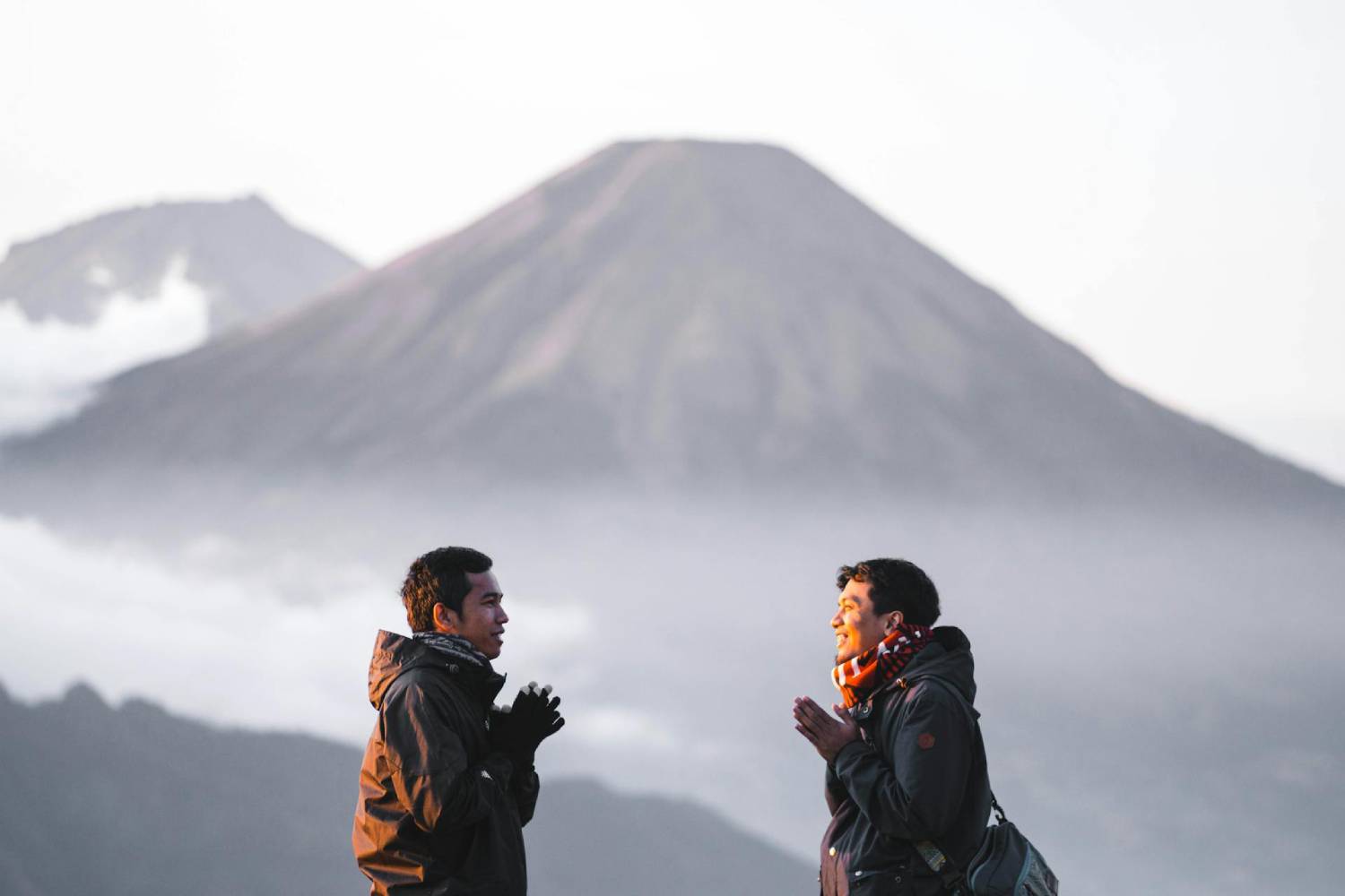 a man and woman facing each other with a mountain in the background