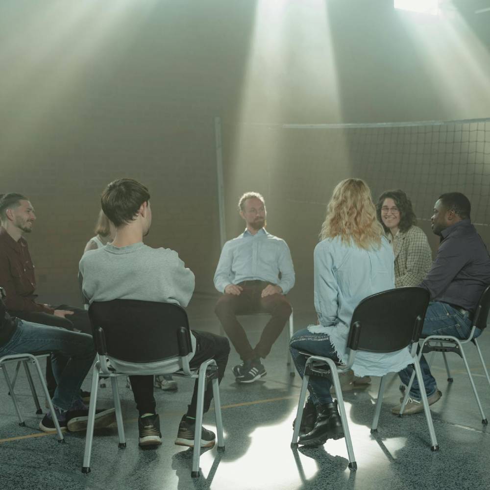 a group of people sitting in a circle for a therapy session
