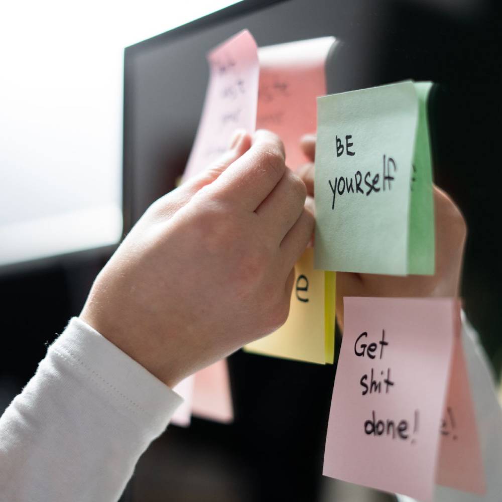 Person placing motivational sticky notes on a monitor