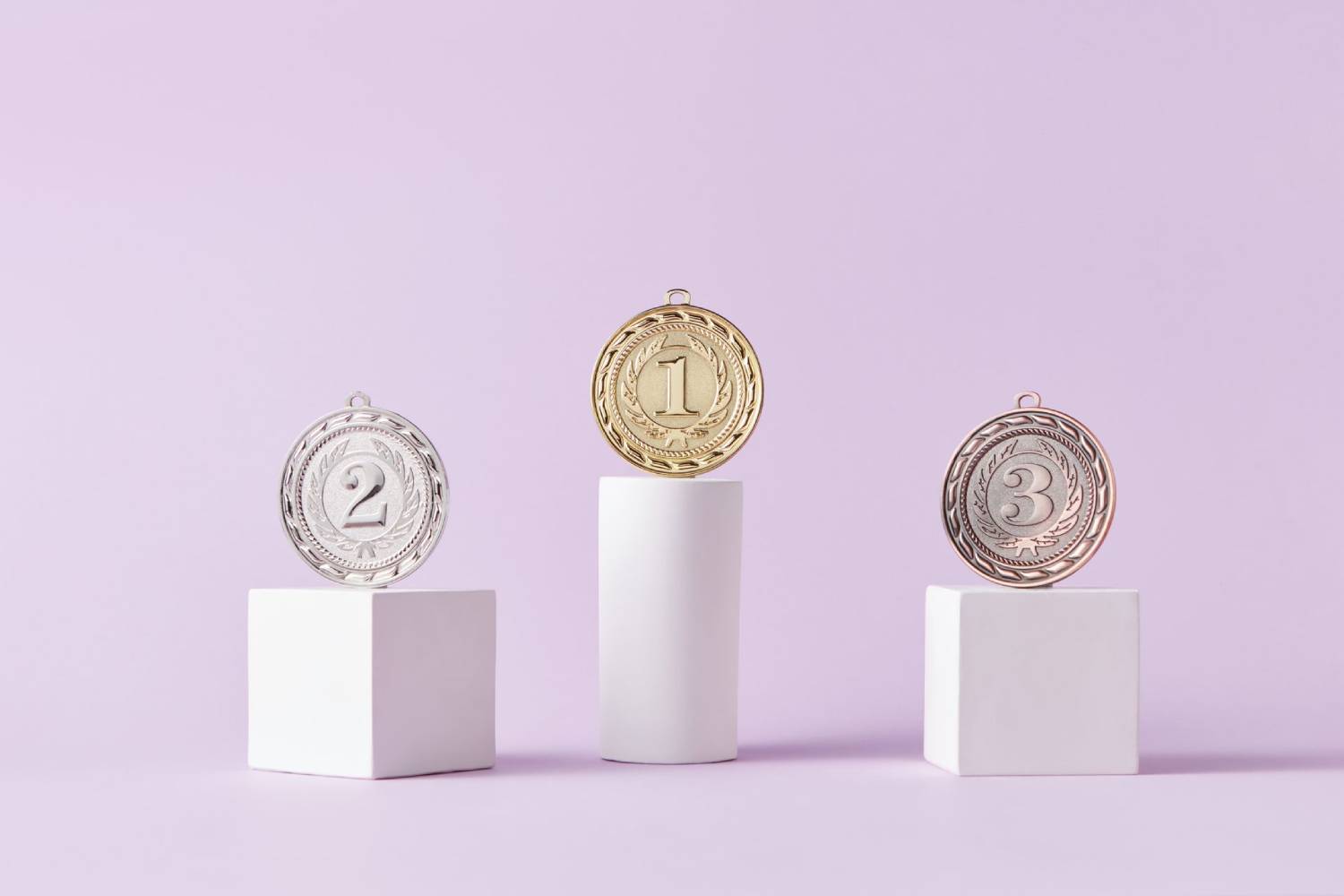 Gold, silver, and bronze award medals displayed on podium blocks, representing first, second, and third place achievements.