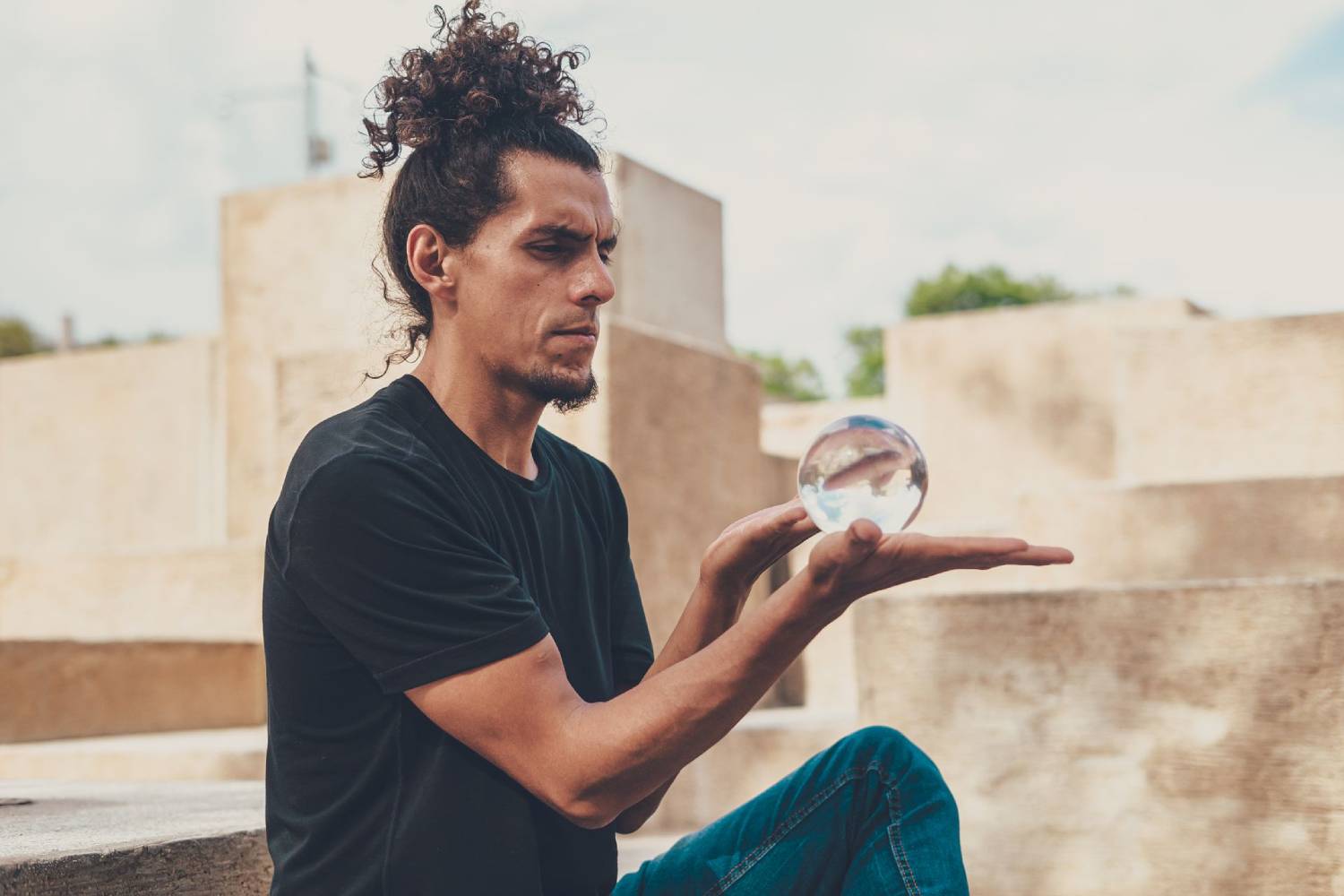 A street performer holds a crystal ball, showcasing his skill in a captivating outdoor setting.