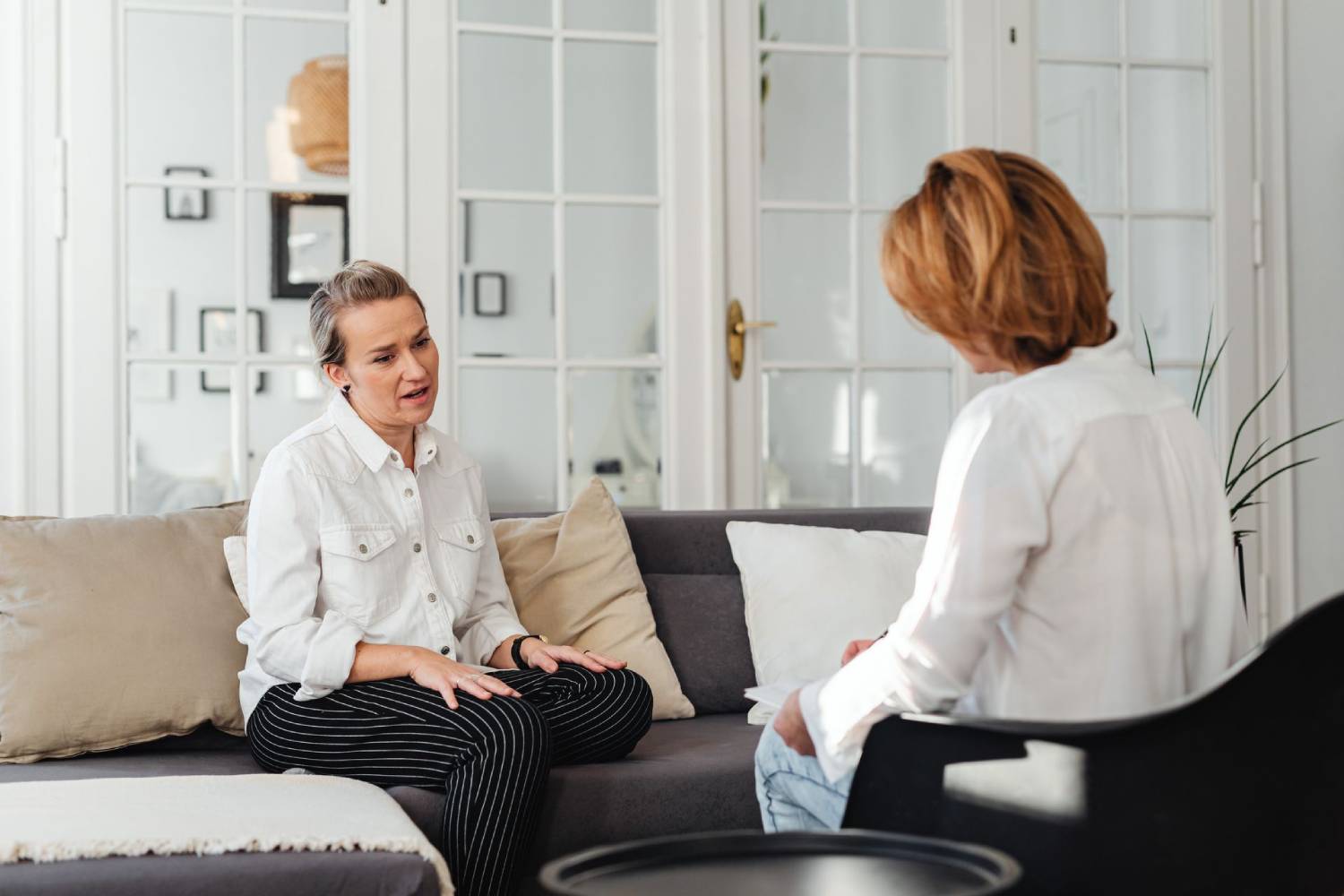 Therapy session with two people seated and talking in a bright, comfortable office.