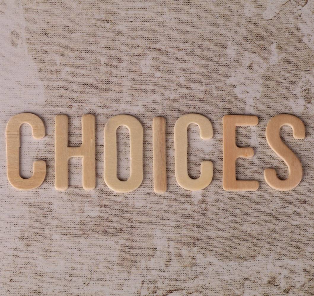 Wooden letters spelling Choices arranged on a textured neutral background.