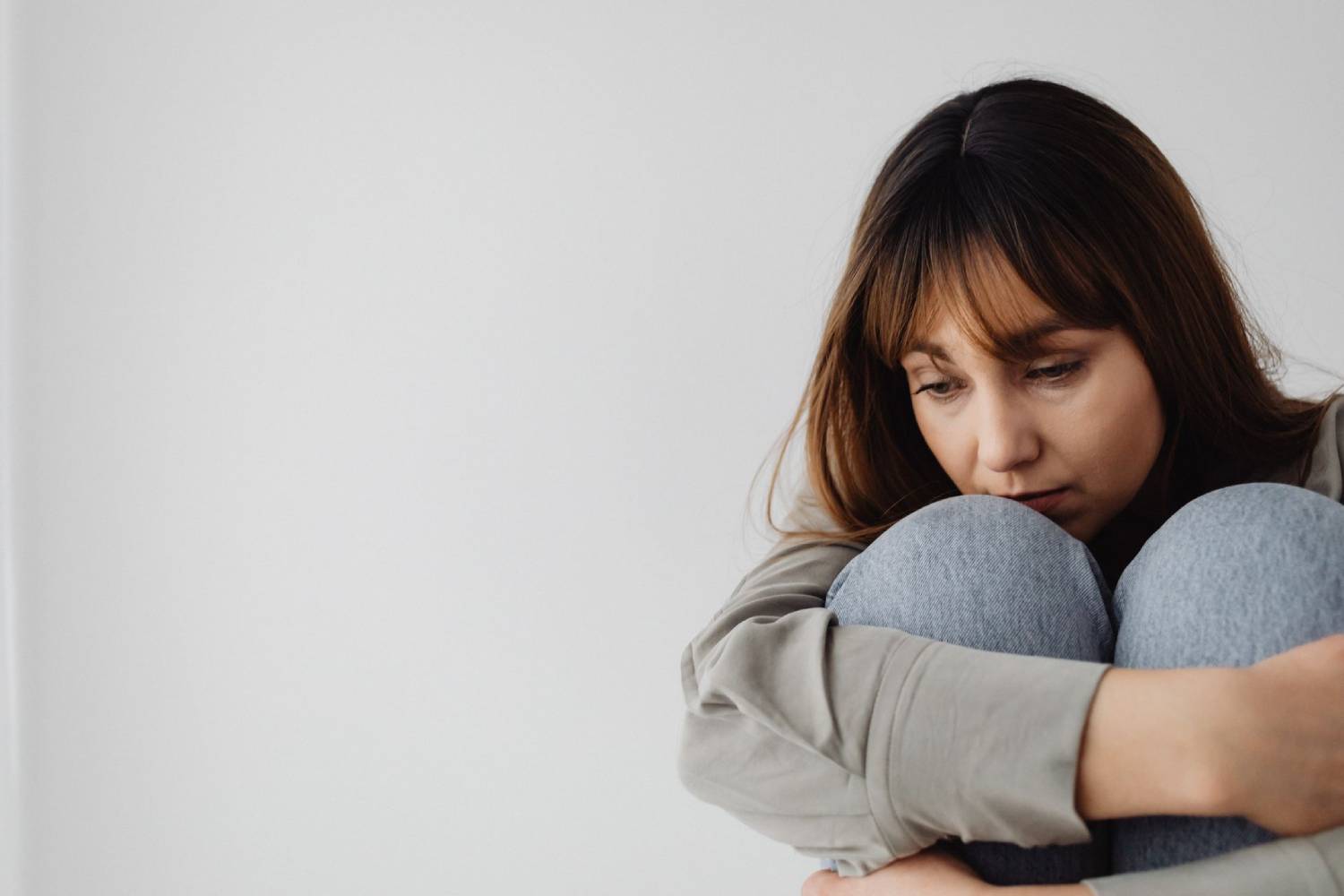 Woman hugging her knees with a contemplative expression.