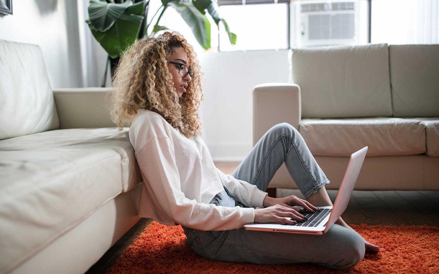 a woman sitting on the floor using a laptop computer